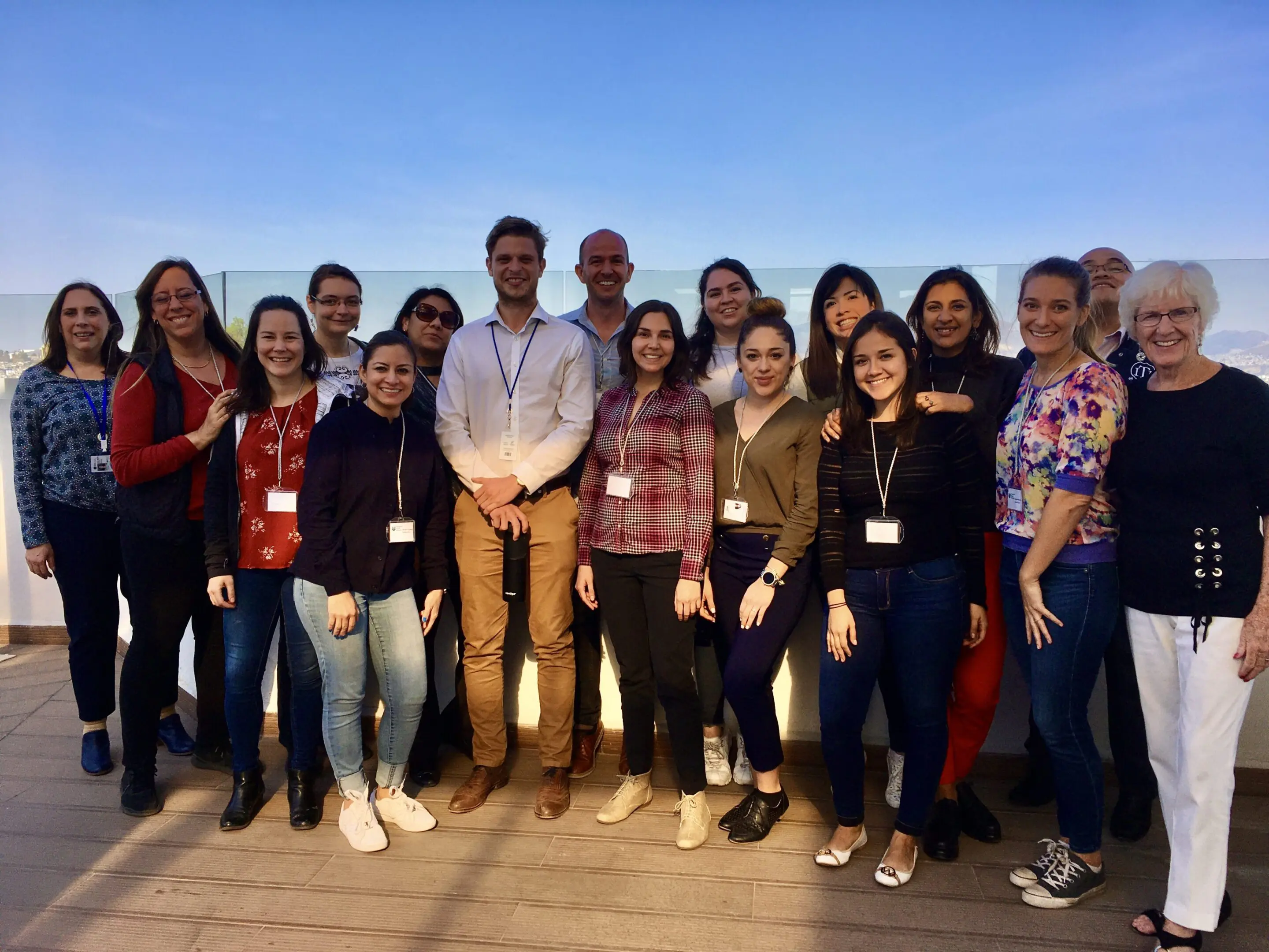 Group of diverse people smiling on a rooftop at sunset.